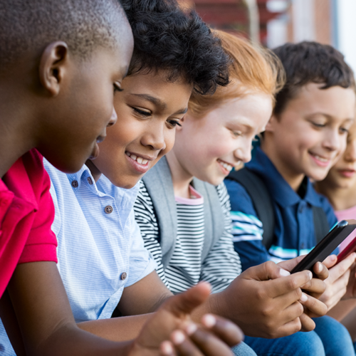 Kids looking at phone; 5 Reasons We're Cautious About Facebook’s Plans to Launch Instagram for Kids
