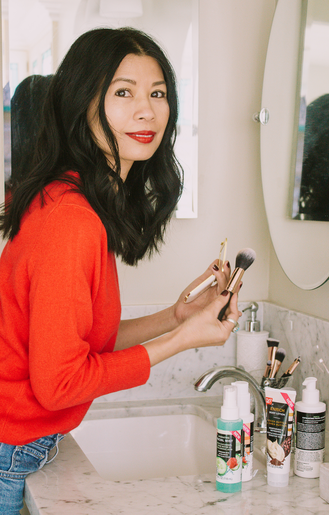 Influencer applying makeup with a brush while holding a mirror, part of a Walgreens Beauty campaign